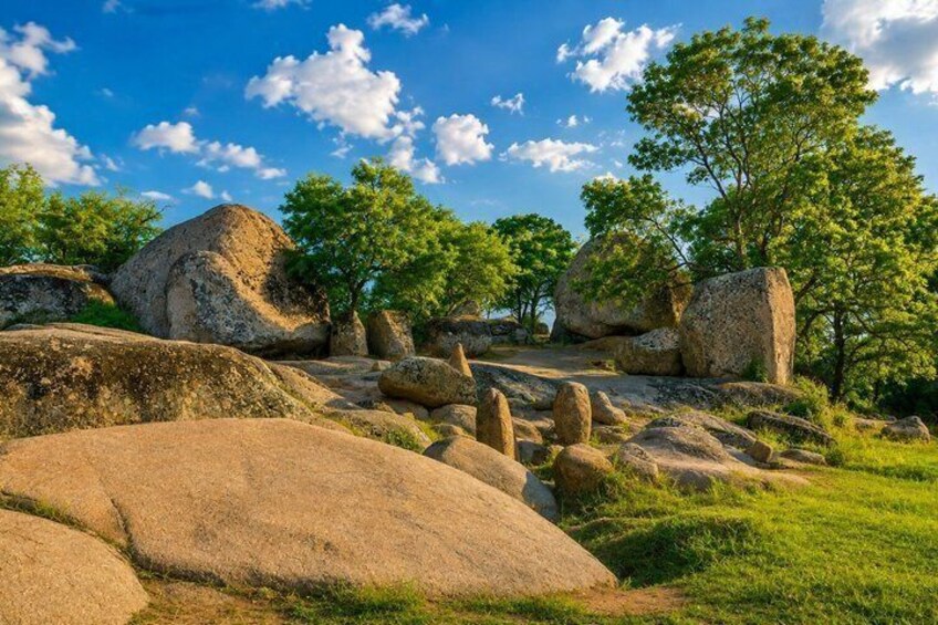 A landscape with large boulders, trees, and a clear sky. 3