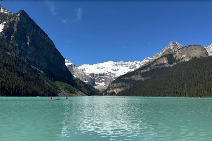 A calm lake surrounded by mountains with kayaks in the water. 3