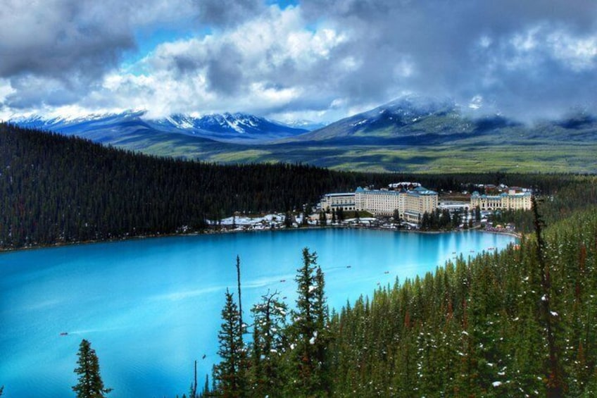 A lake surrounded by forest and mountains, with a resort building in the background. 1