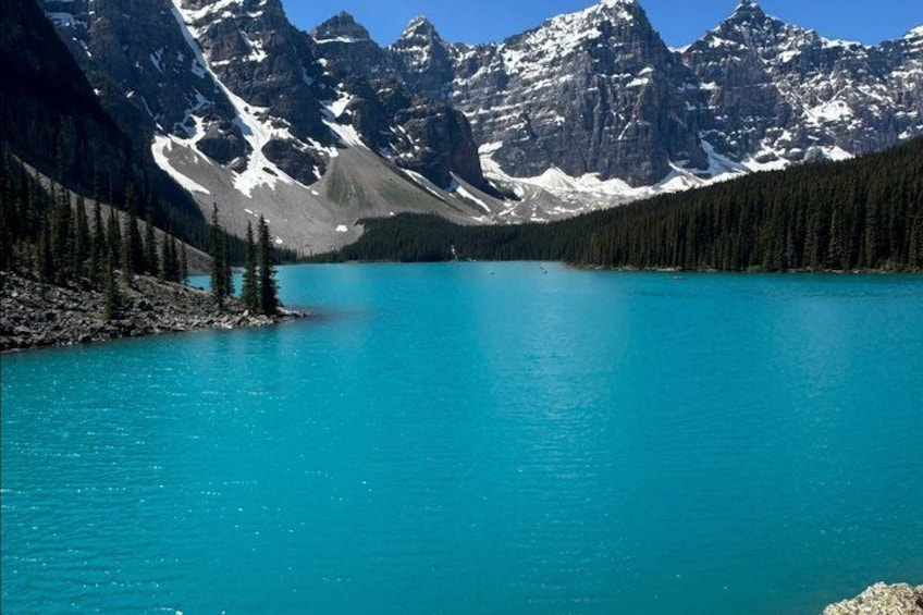 A turquoise lake surrounded by snow-capped mountains and dense forest. 4