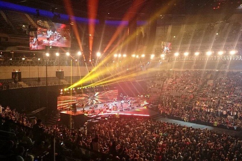 A large indoor concert venue with a stage, audience, and stage lighting. 5