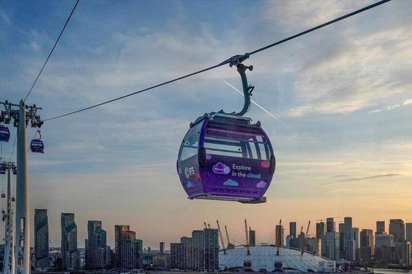 A purple cable car with 'Explore in the cloud' text, suspended above a cityscape with buildings and a bridge. 3