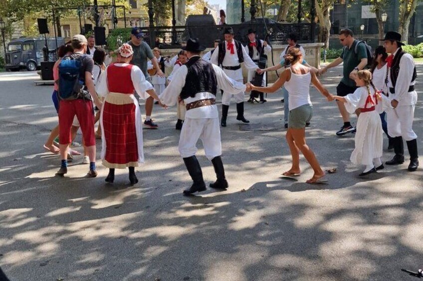 A group of people in traditional costumes dancing in an outdoor setting. 3