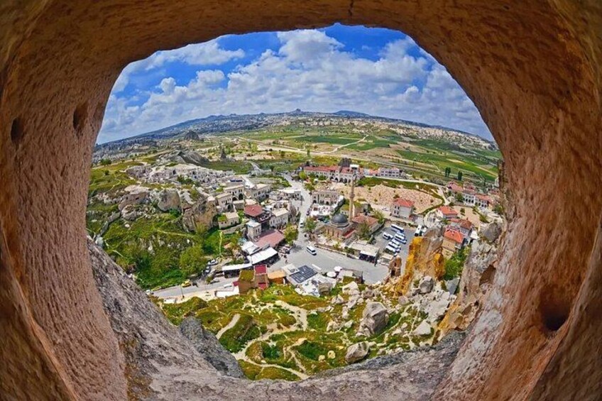 A panoramic view of a town with buildings, roads, and green hills. 3