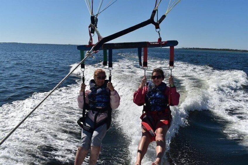 Zwei Personen windsurfen auf einem gewellten Gewässer. 2