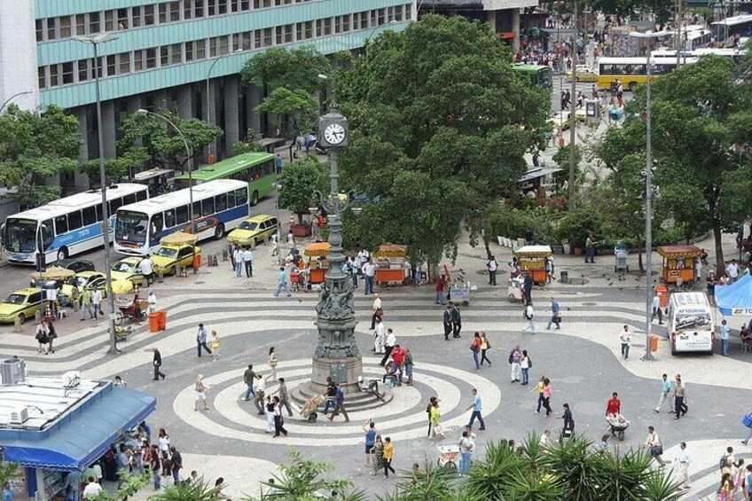 A busy urban square with a central monument, surrounded by pedestrians and vehicles. 4