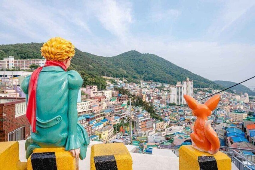 A person in a teal coat and red scarf overlooking a cityscape with a mountain in the background. 5