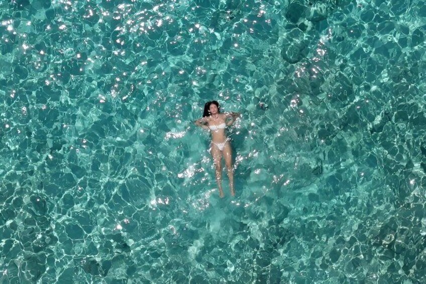 A person floating in clear blue water. 5