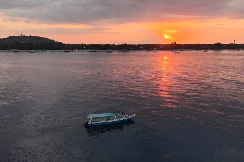 A boat on calm water during sunset with a distant shoreline and a hill. 2
