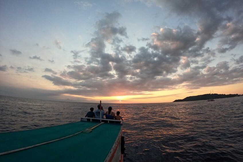 A boat with people on a calm sea during sunset. 5