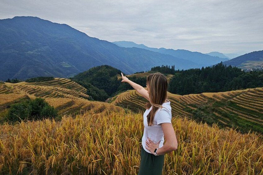 A person standing in a field of tall grass with a mountainous landscape in the background. 4