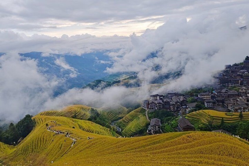 Terraced rice fields, a village with traditional houses, and a mountain range partially covered by clouds. 1