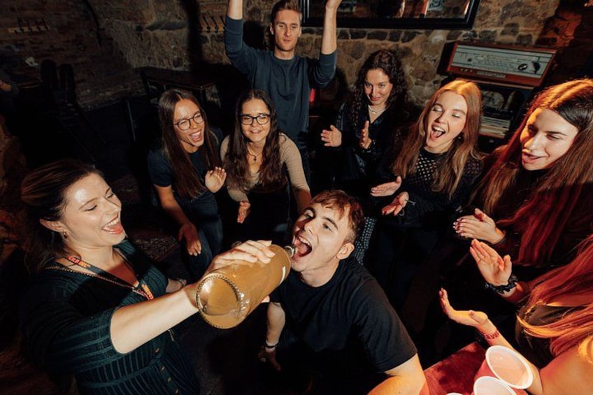 A group of people clapping and cheering in a dimly lit room with stone walls. 1