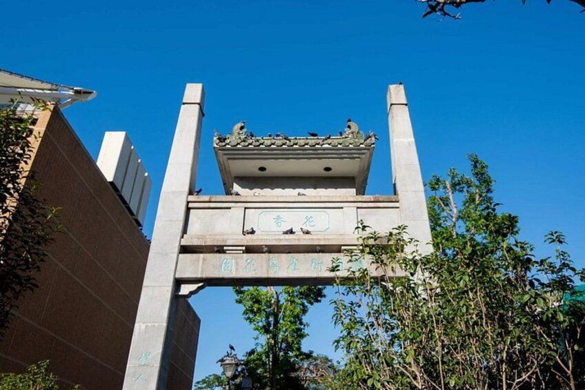 A traditional Chinese gate with inscriptions, surrounded by trees and a clear blue sky. 3