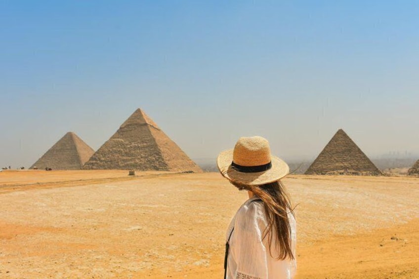 A person in a hat standing in front of the pyramids. 4