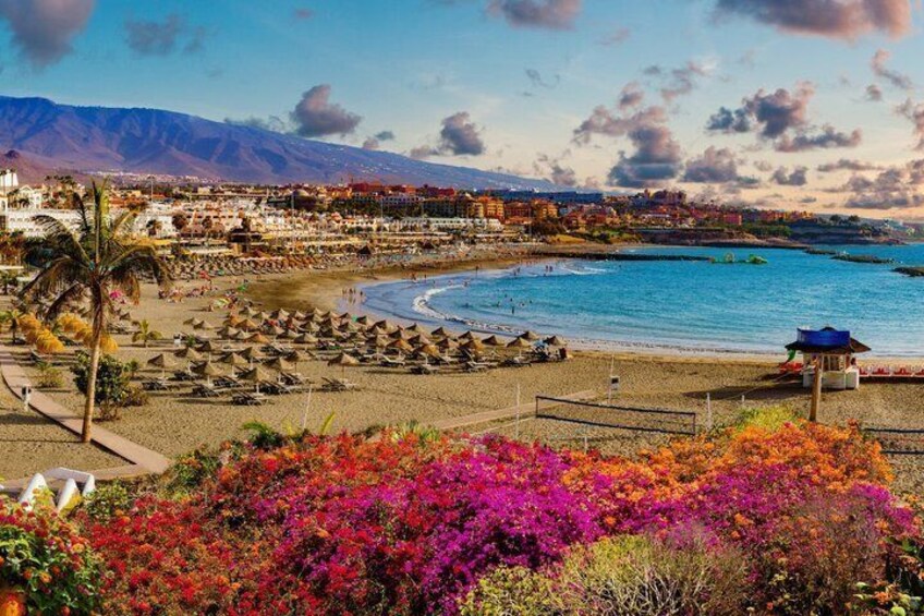 A beach with umbrellas, a water body, and mountains in the background. 3
