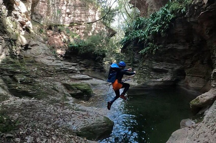Una persona saltando sobre un río en un cañón rocoso. 4