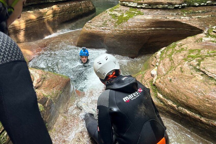 Una persona con traje de neopreno y casco observa a un kayakista en un río. 3