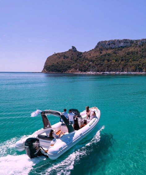 A boat with people on a turquoise sea, a rocky hill in the background, and a clear sky. 1