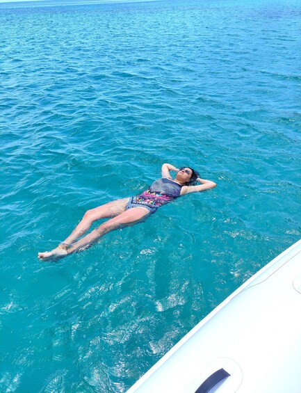 A person floating on a boat in a turquoise sea. 3
