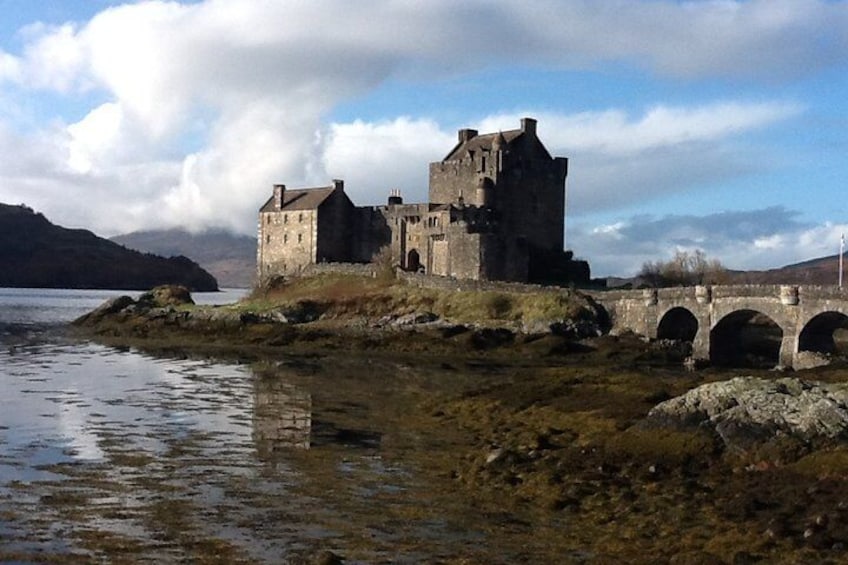 A historic castle by a lake with a bridge leading to it. 4