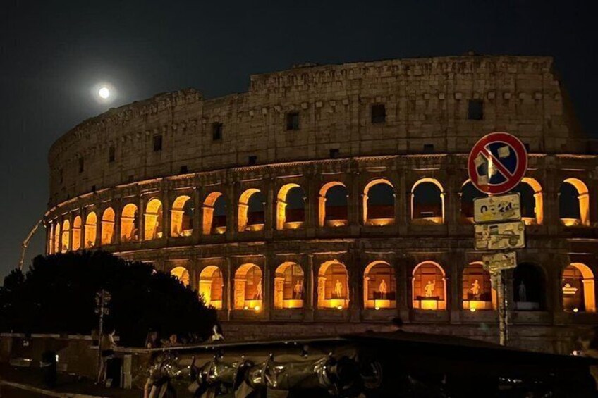 The Colosseum at night with the moon visible in the sky. 5
