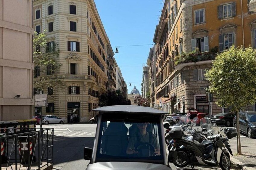 A street with parked motorcycles, a car, and buildings with balconies. 3