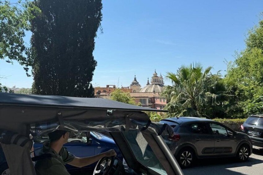 A parked car with a roof rack, a blue car, and a building with domes in the background. 2