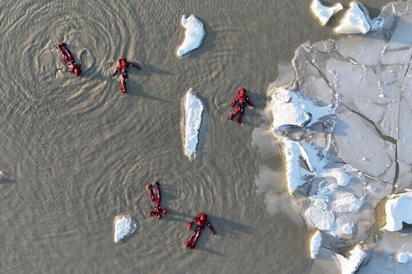 A group of people in red suits on a frozen lake surrounded by ice. 4
