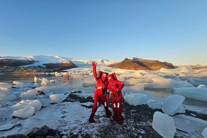 Dos personas con abrigos rojos sobre hielo, con montañas al fondo. 1