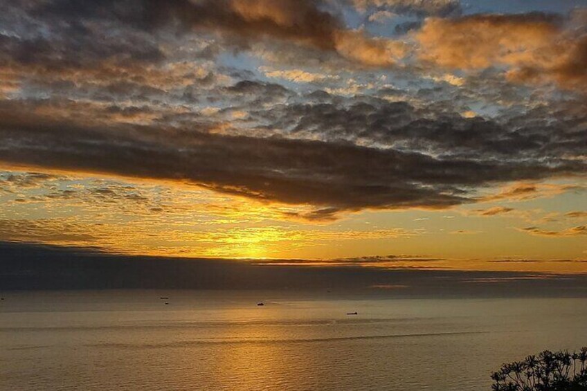 A sunset over a calm sea with a cloudy sky. 4