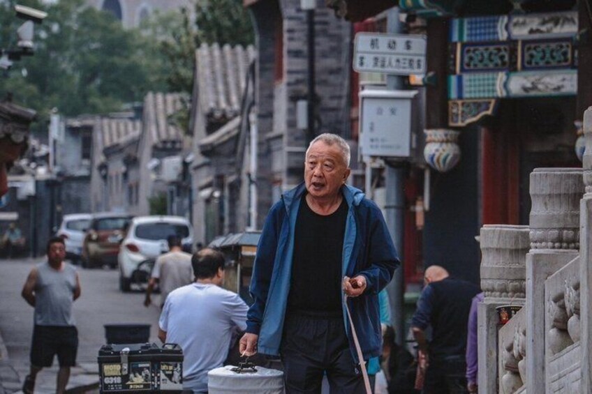 A street scene with a man walking, traditional buildings, and a parked car. 1