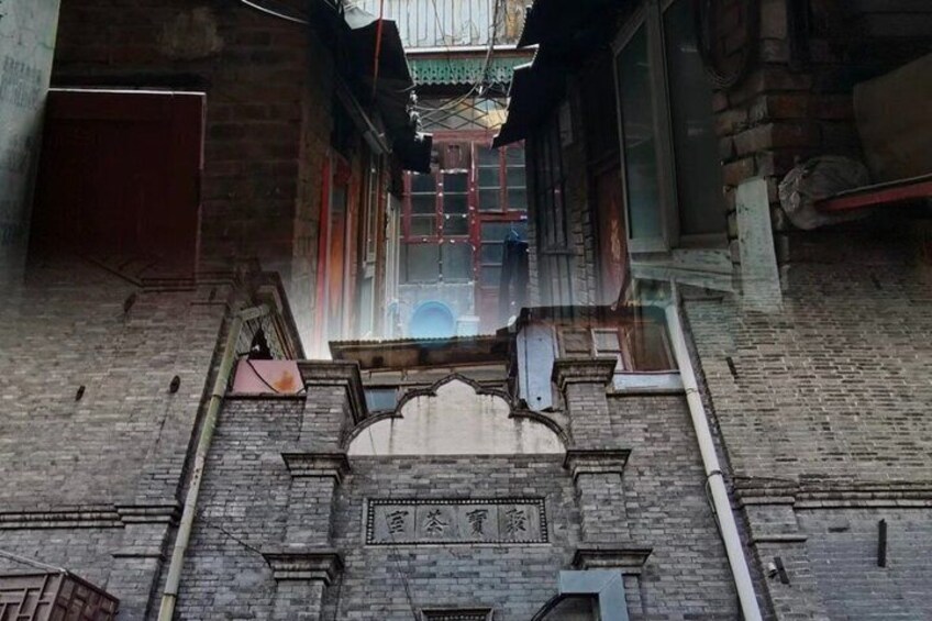 A narrow alleyway with a brick wall, a wooden door, and a metal gate at the end. 4