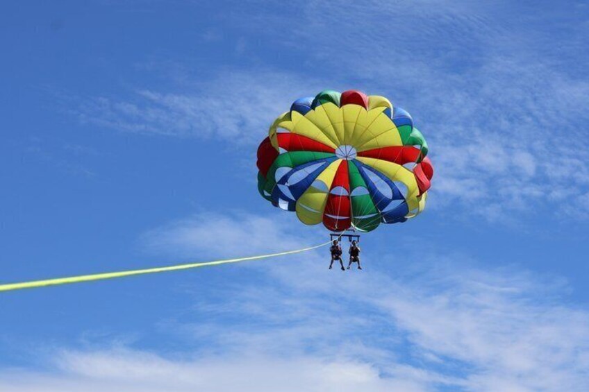 A person skydiving with a colorful parachute against a clear blue sky. 1