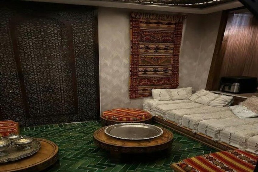 A traditional room with a patterned wall, a sofa with cushions, a tray with a bowl, and a patterned rug. 3