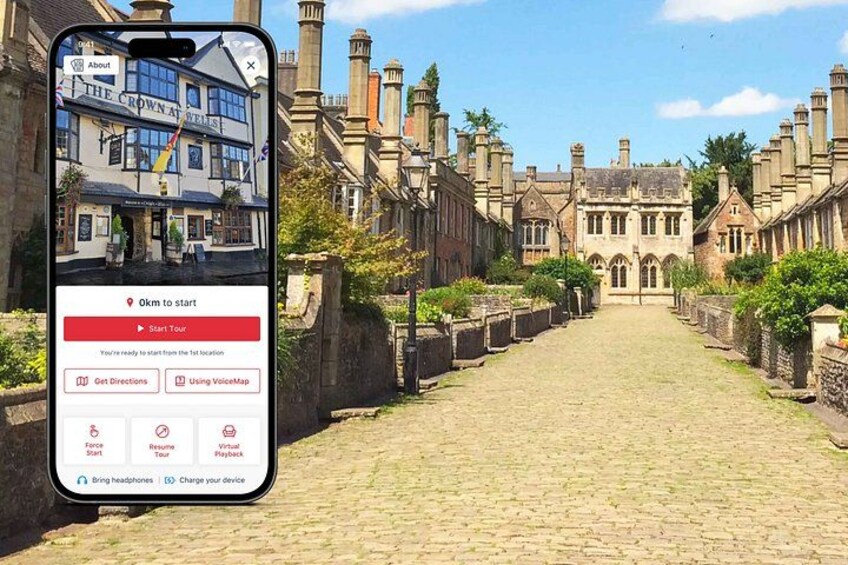 A smartphone displaying a virtual tour of a historic street with cobblestone pavement and traditional buildings. 1