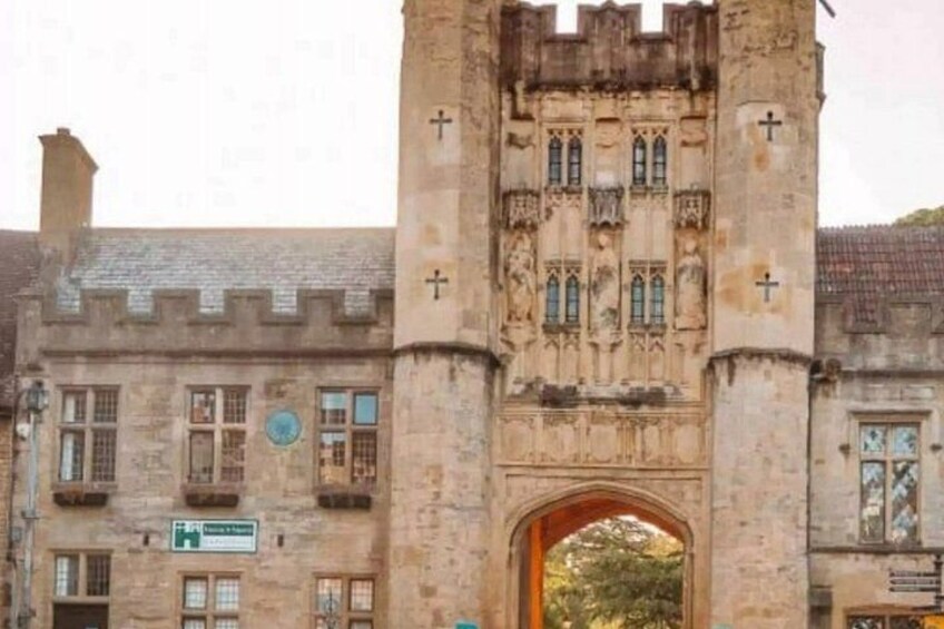 A historic stone building with a tall tower, arched entrance, and a sign. 4