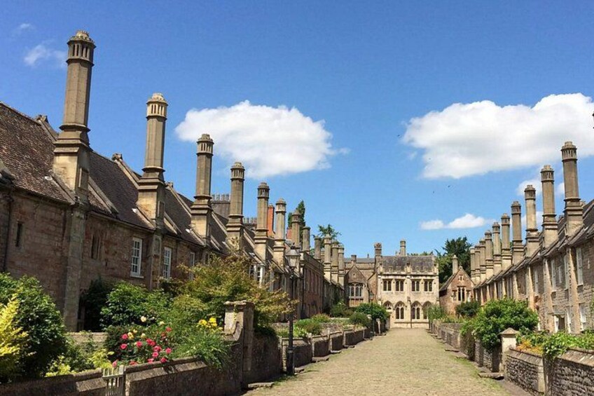 A historic street lined with buildings, a cobblestone path, and a clear blue sky. 3