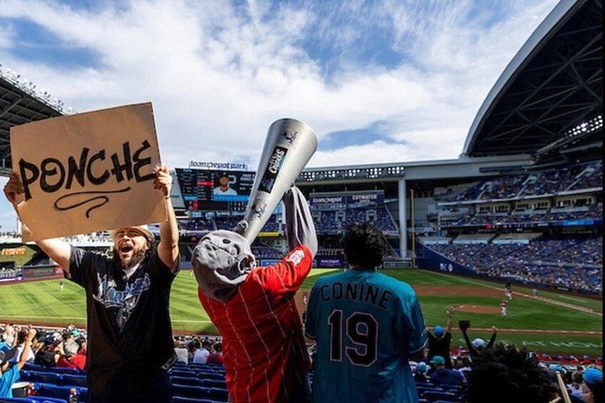 Un estadio de béisbol con una multitud, una persona sosteniendo un bate y un letrero que dice 'PONCHE'. 3