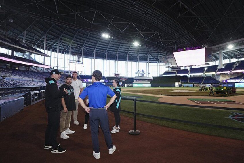 Un estadio interior con un campo de béisbol, un marcador y un grupo de personas de pie en el campo. 5