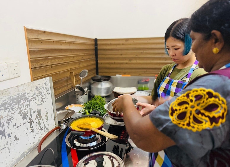 Two people cooking in a kitchen with wooden walls and a gas stove. 1
