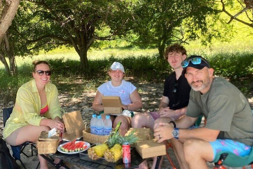 Four people sitting outdoors with food and drinks. 4