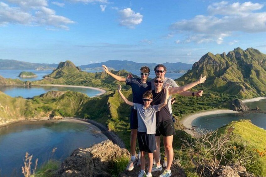 A family standing on a cliff overlooking a coastal landscape with mountains and a bay. 3
