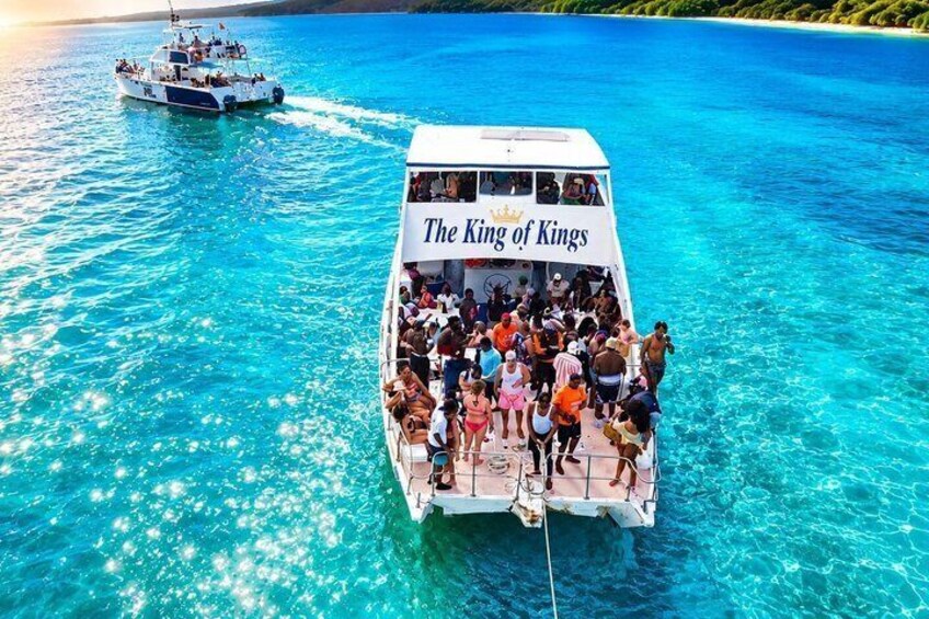 Un barco llamado 'The King of Kings' con pasajeros en un mar azul y despejado. 2