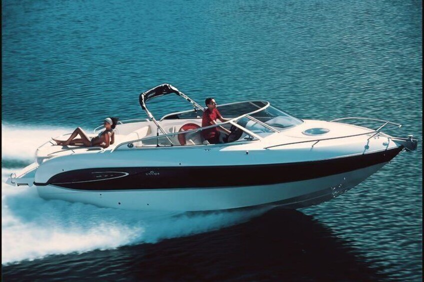 A speedboat with two people on board, one at the front and one at the rear, moving through calm water. 4