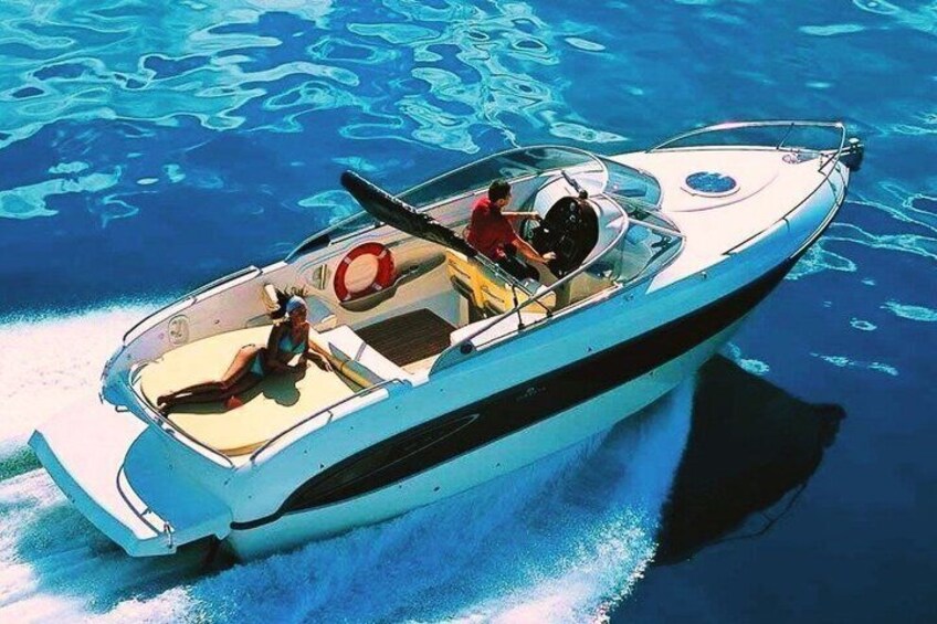 A small motorboat with two people on board, moving through clear blue water. 3