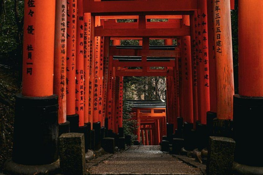 En traditionell japansk torii-port med röda pelare och svarta socklar, som leder fram till ett tempel. 1