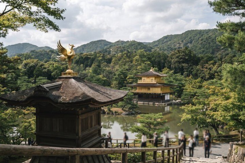 Un temple japonais traditionnel, orné d’une statue de coq en or, entouré d’une végétation luxuriante et bordé d’un étang paisible. 2