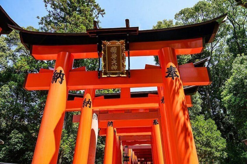 Un torii japonés tradicional con pilares rojos y una placa dorada. 5