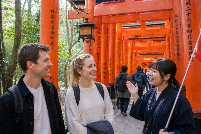 Un gruppo di persone in piedi di fronte a un torii rosso in una zona boschiva. 3